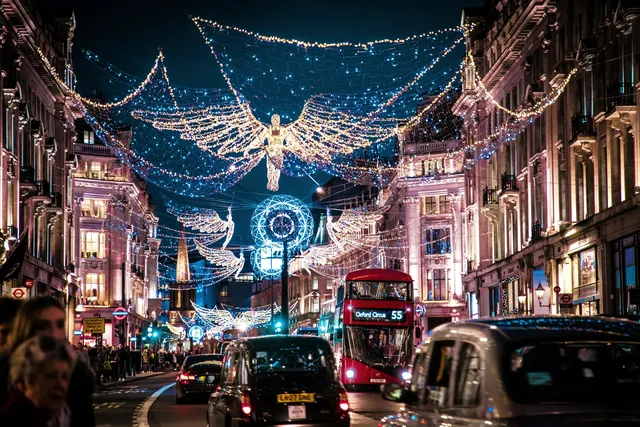 Christmas light angels over Regent Street in London at night, with a red bus