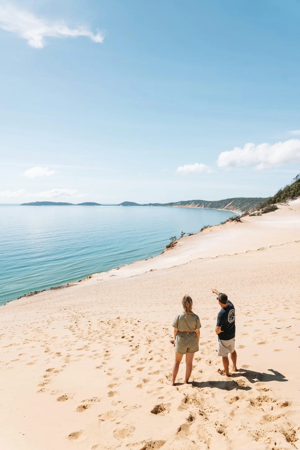 Two travellers on a wide sandy beach overlooking the ocean